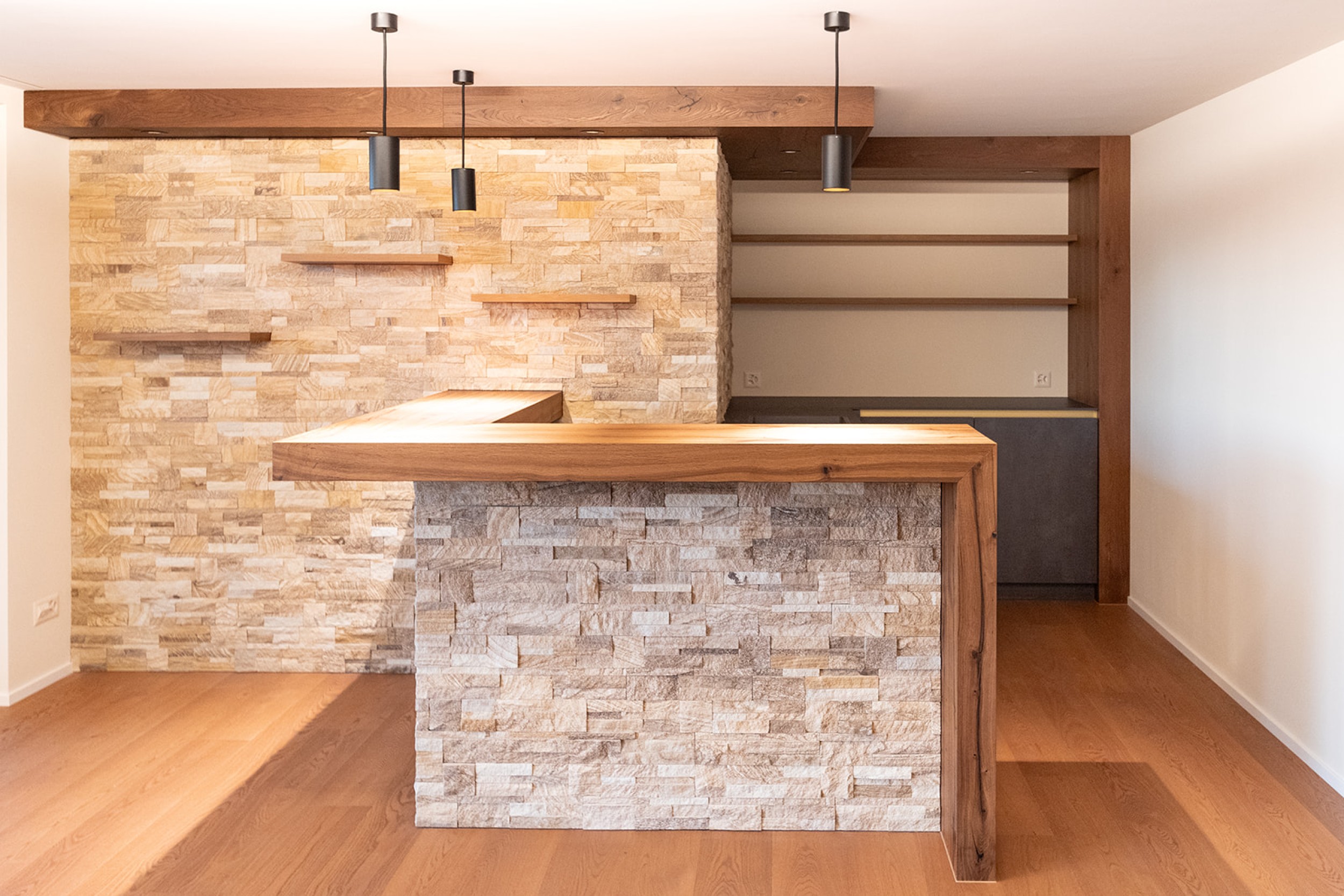 Modernes Untergeschoss mit Barbereich, kombiniert aus rustikalem Steinmauerwerk und hochwertigen Holzakzenten.