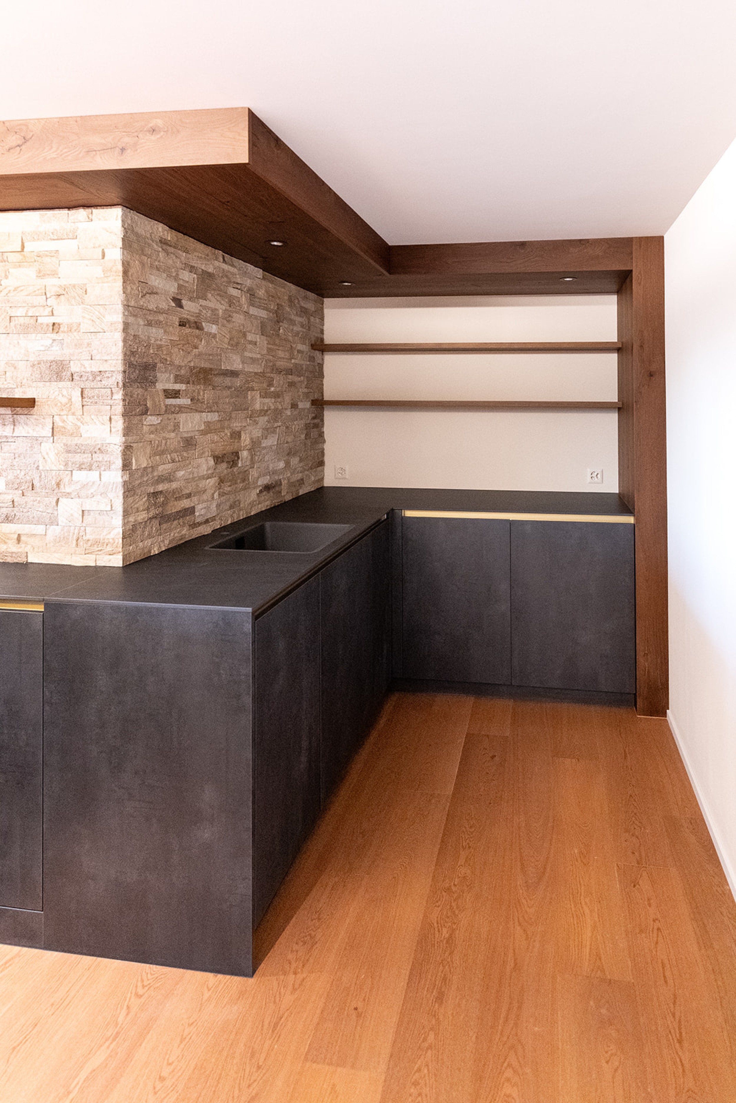 Modernes Untergeschoss mit Barbereich, kombiniert aus rustikalem Steinmauerwerk und hochwertigen Holzakzenten.