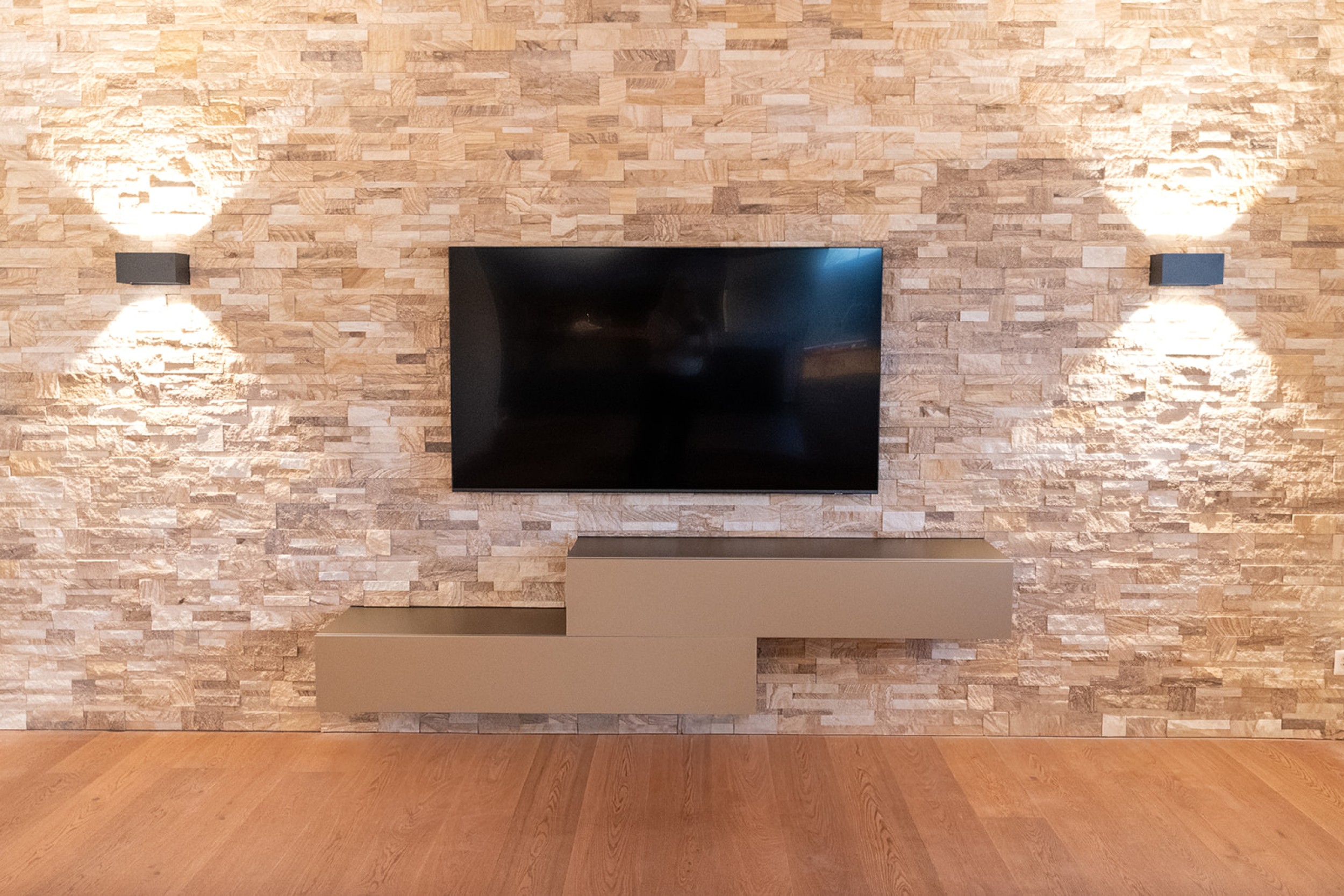 Modernes goldenes Wohnzimmermöbel, kombiniert mitt rustikalem Steinmauerwerk und hochwertigen Holzakzenten.